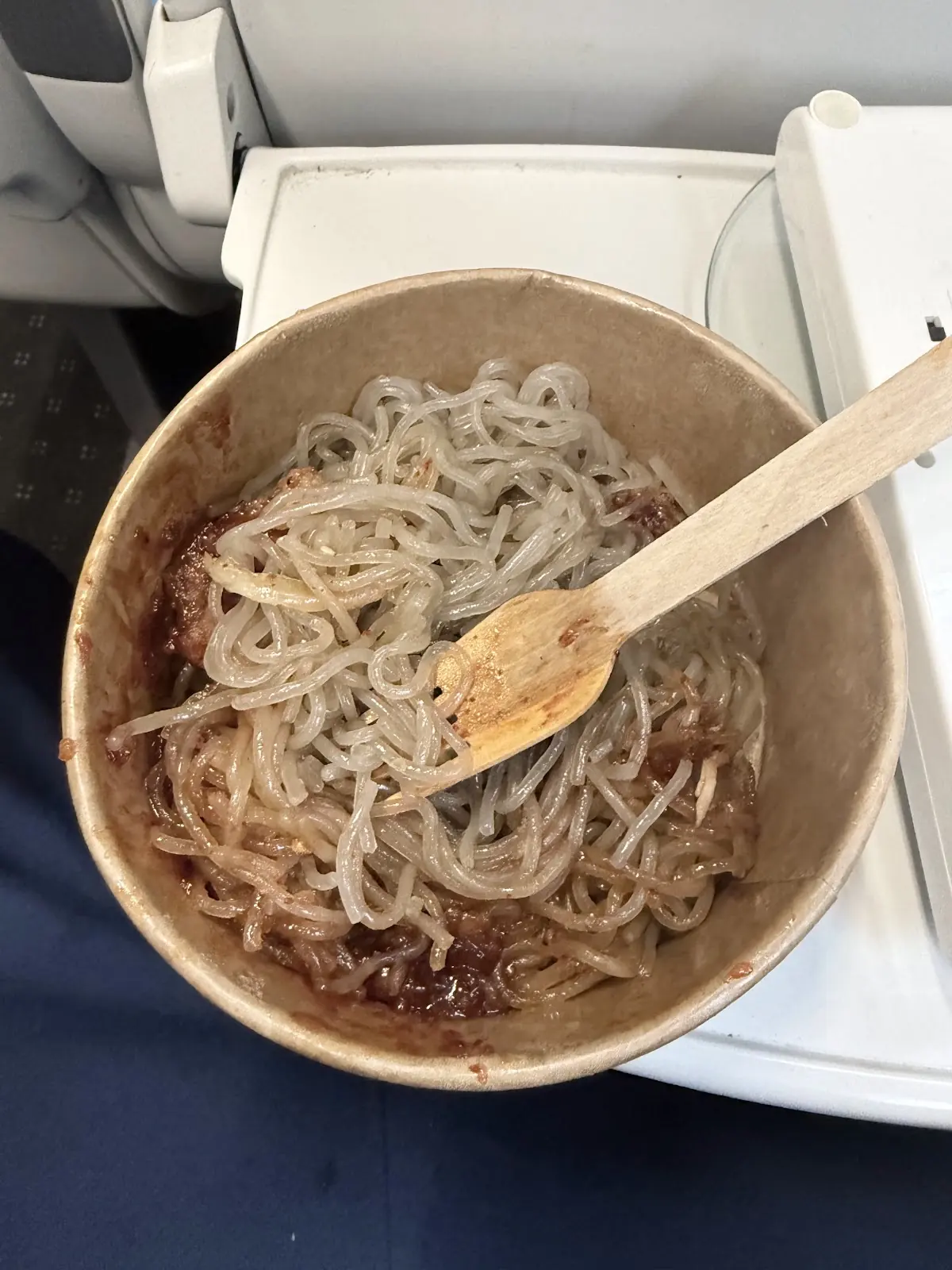 Close overhead of glass noodles over beef with a wooden fork resting in the bowl