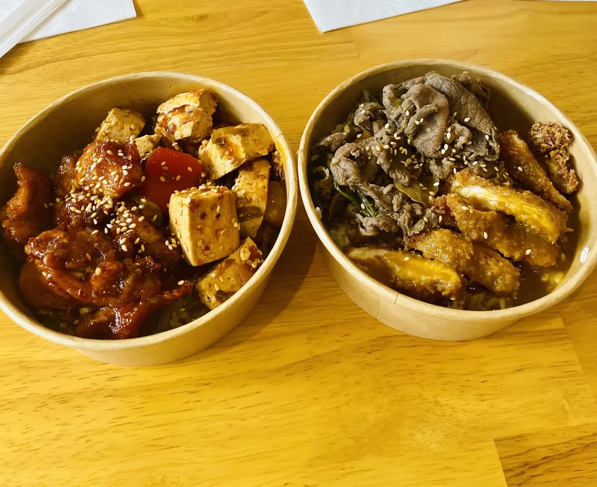 Two kraft bowls side by side, tteokbokki with tofu and sesame beside beef bulgogi with rice cake